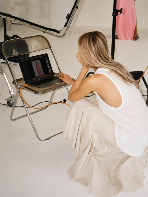 Creative director reviewing campaign photography on a laptop during a studio shoot