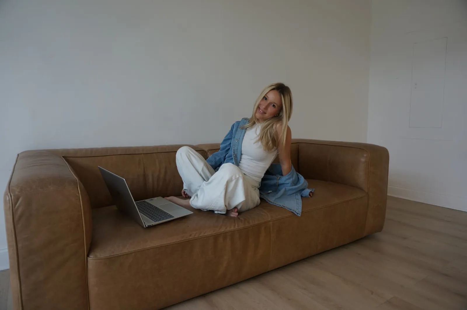 Cala Creative founder seated on a leather sofa with her laptop